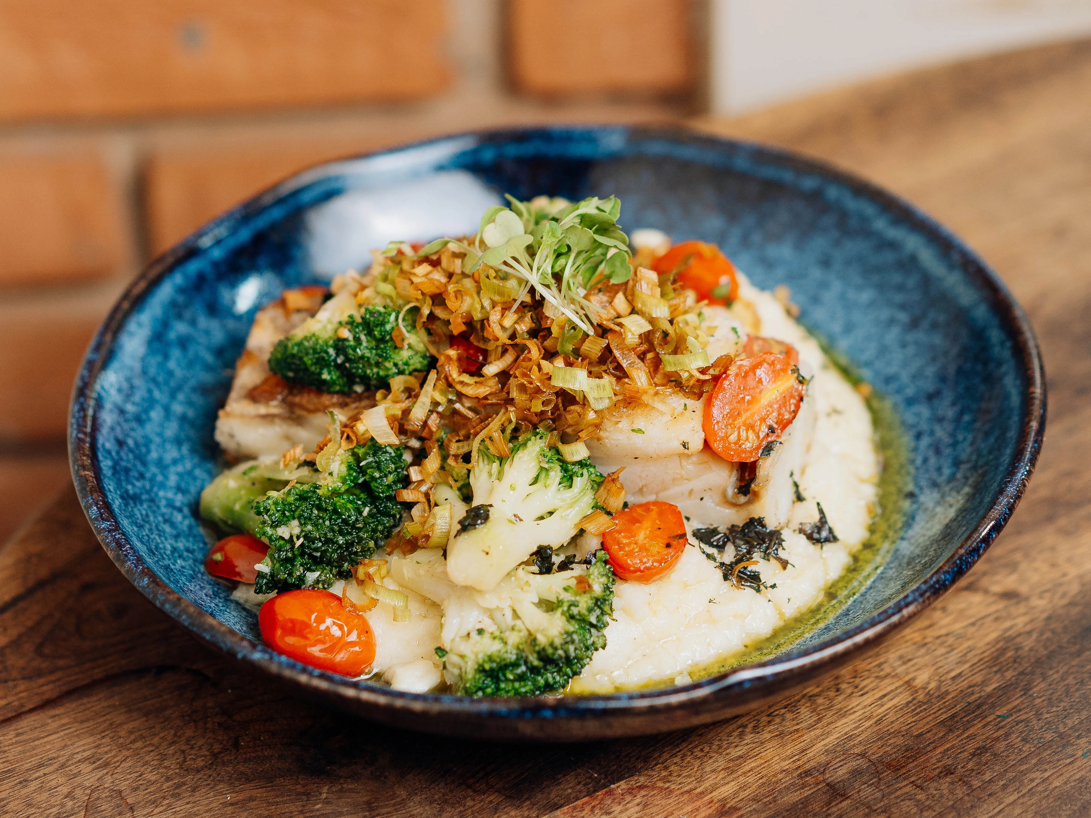 Bacalhau em cama de purê de batatas, brócolis, tomate cereja e crispy de alho-poró